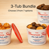 Three tubs of The Macaroon Shop with red lids on a wooden surface.