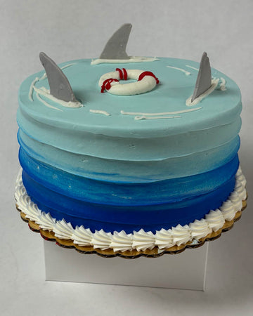 Cake with shark fins and a life preserver on a gray background