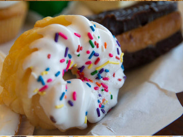 Cookie with white icing and colorful sprinkles on a blurred background