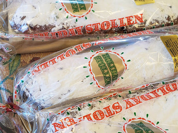 Two packages of holiday stollen with visible branding on a patterned surface.